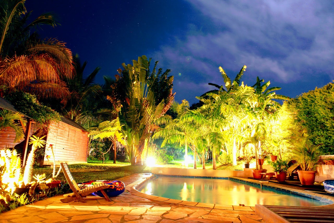 une vue de nuit de la piscine et du jardin